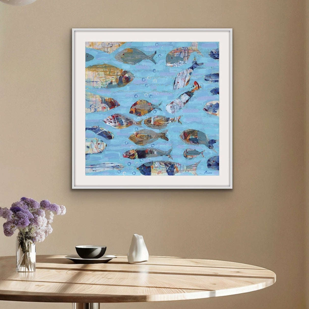 Framed painting of colorful fish on a wall above a wooden table with decor items.