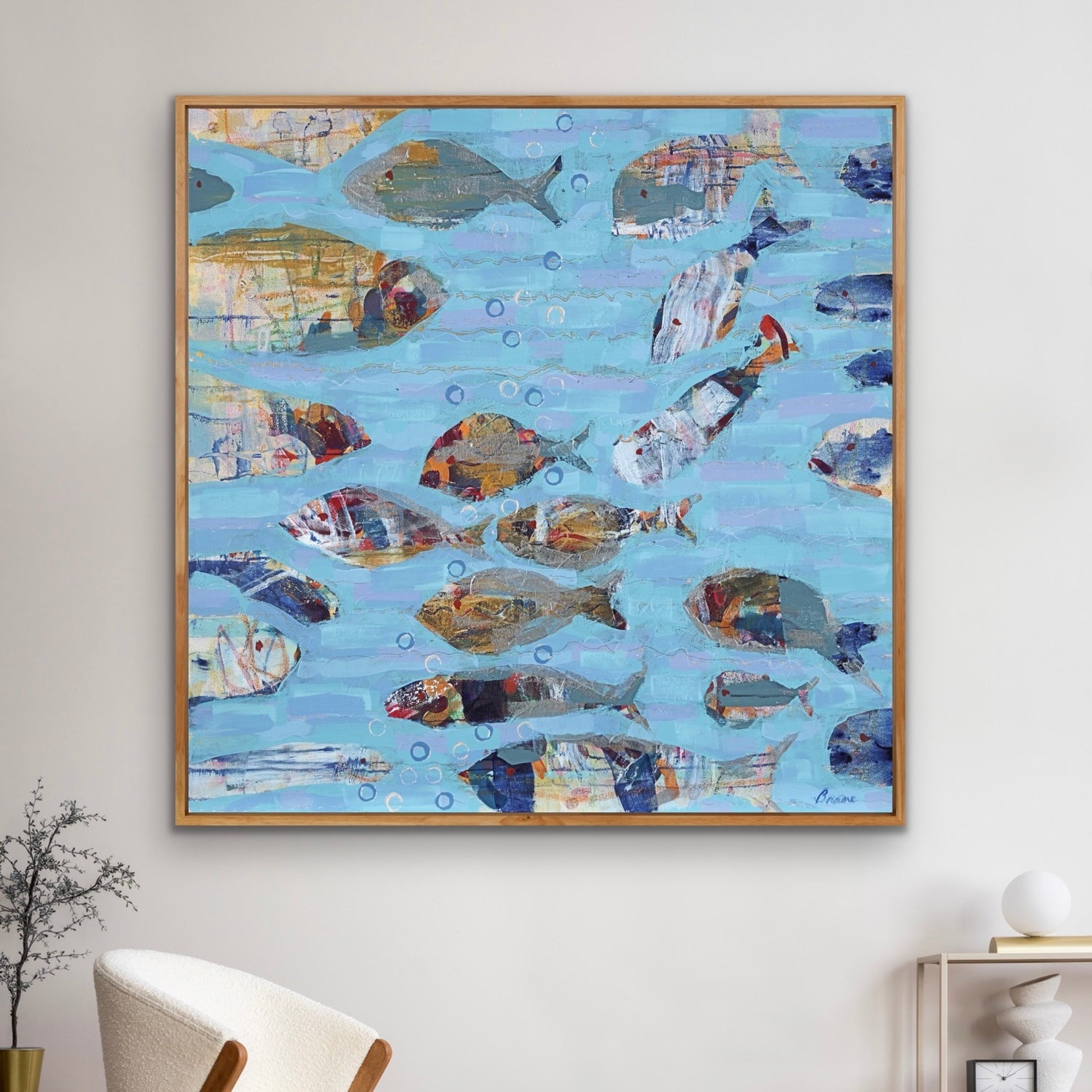 Framed artwork of stylized abstract fish on a blue background, hanging on a wall.