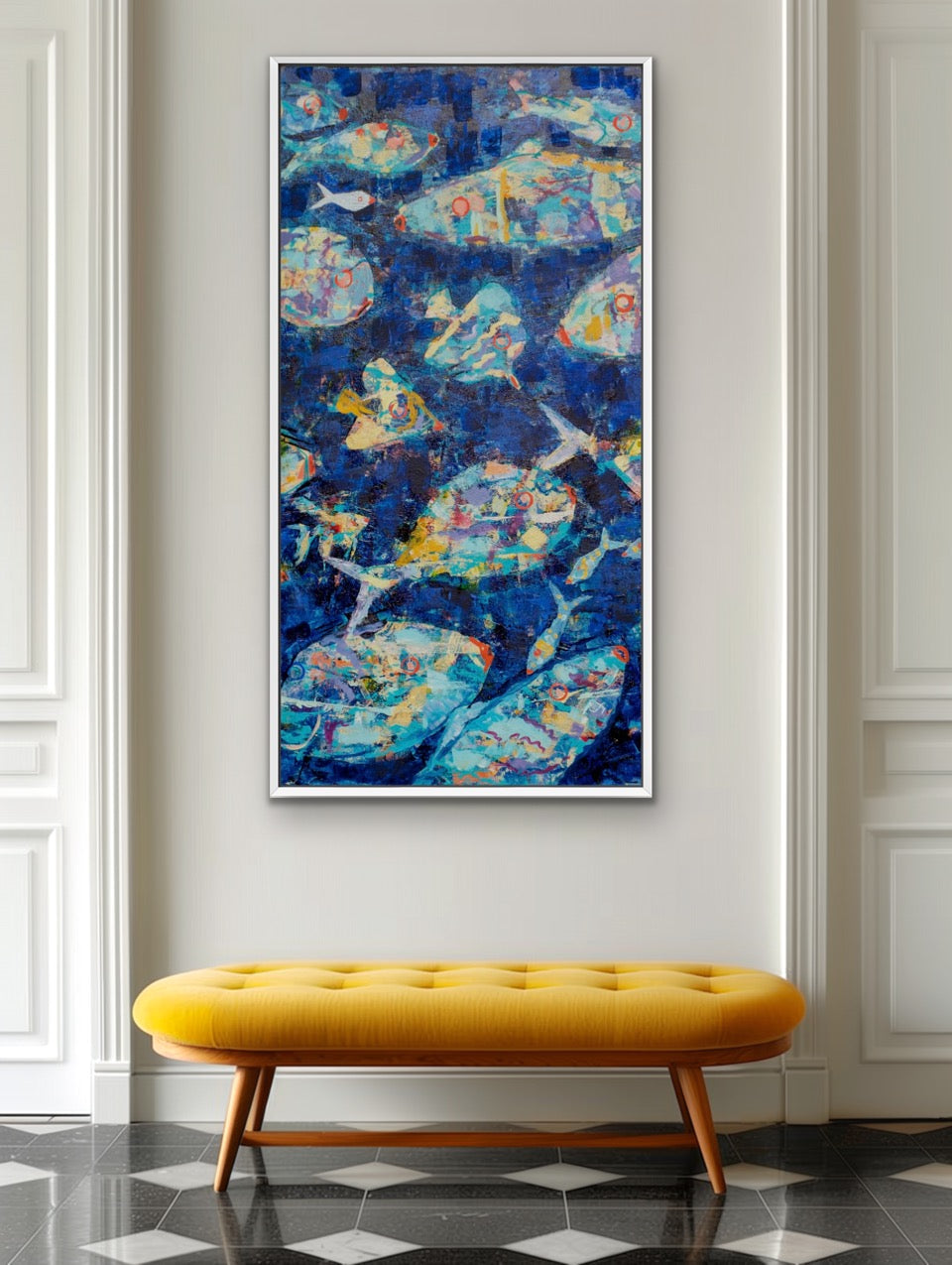A framed abstract painting featuring blue, teal, and yellow fish-like forms, displayed on a light gray wall above a mustard yellow tufted bench in a styled interior setting.