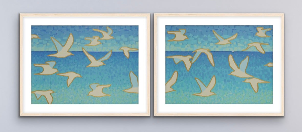Two seaside seagull themed framed artworks of birds flying against a blue sky on a gray background