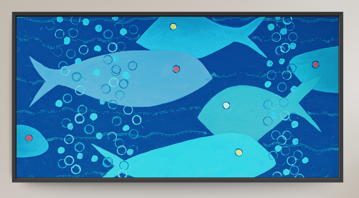 A framed abstract art print depicting stylized blue and light blue fish swimming underwater with bubbles, set against a neutral beige wall.