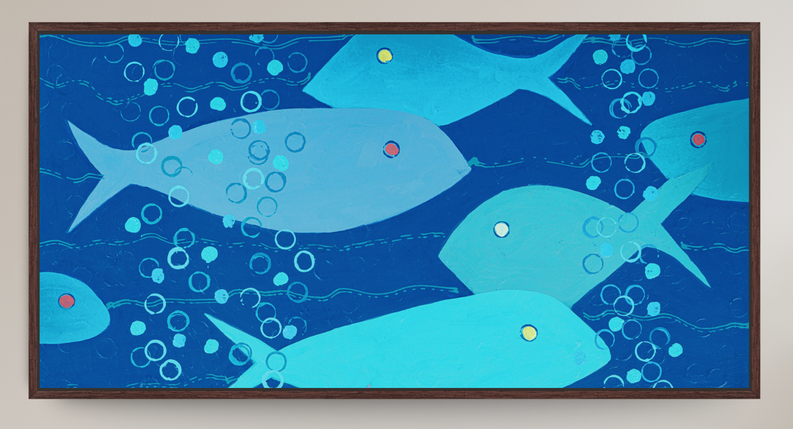 A framed abstract art print depicting stylized blue fish swimming underwater with bubbles, set against a light beige wall.