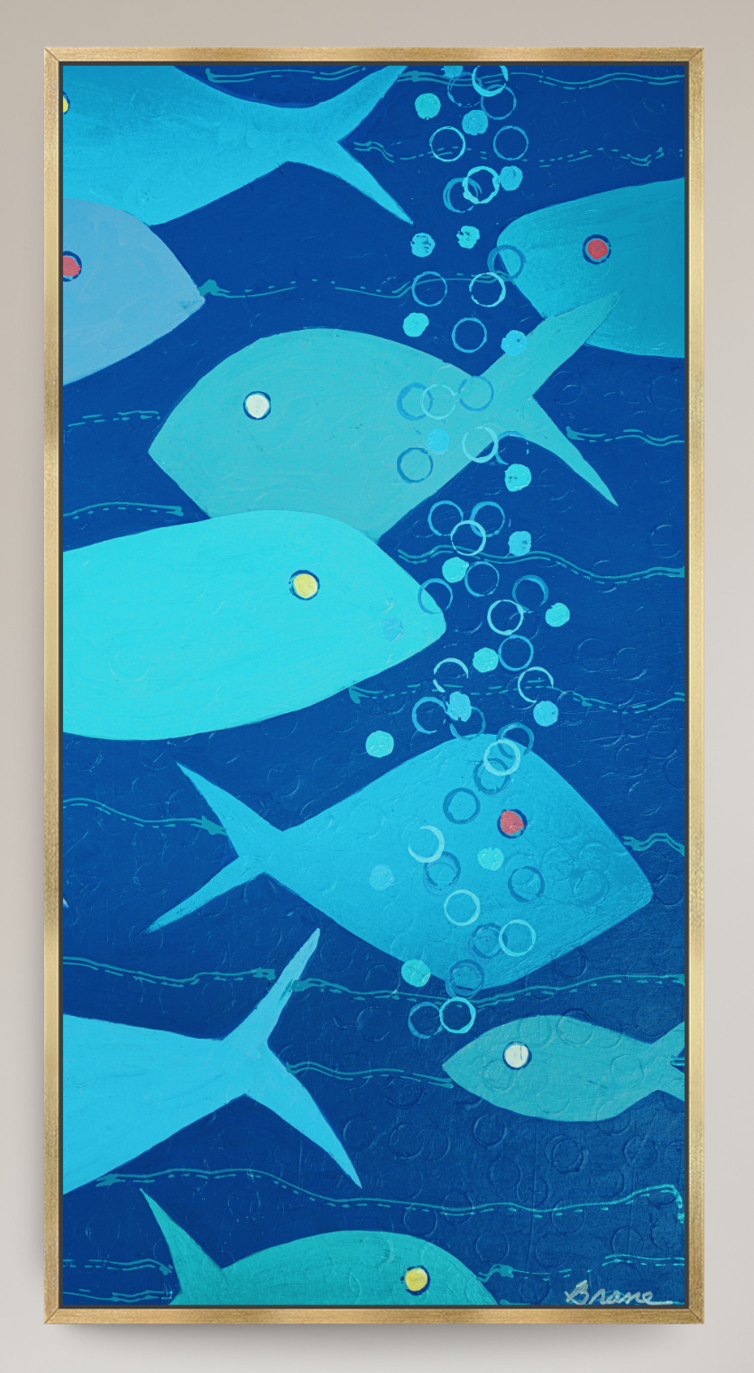 A framed abstract art print depicting stylized blue fish swimming underwater with rising bubbles, set in a thin gold frame against a light beige wall.
