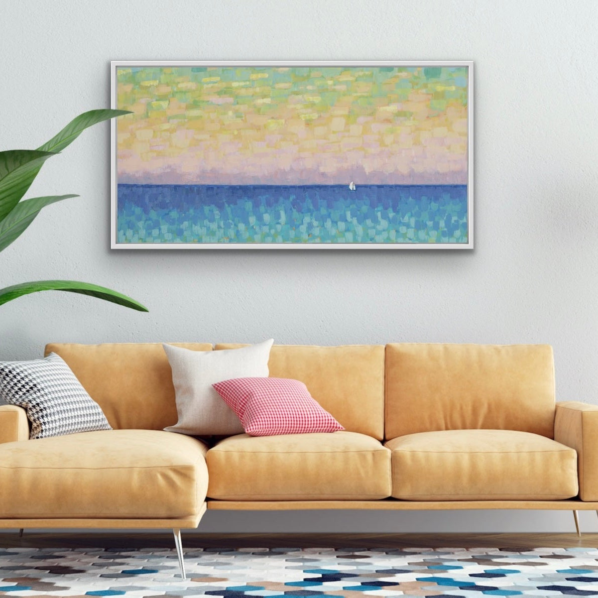 Living room with a beige sofa, colorful rug, and framed panoramic coastal canvas print with soft sunset colors and a small white sailboat on the wall.