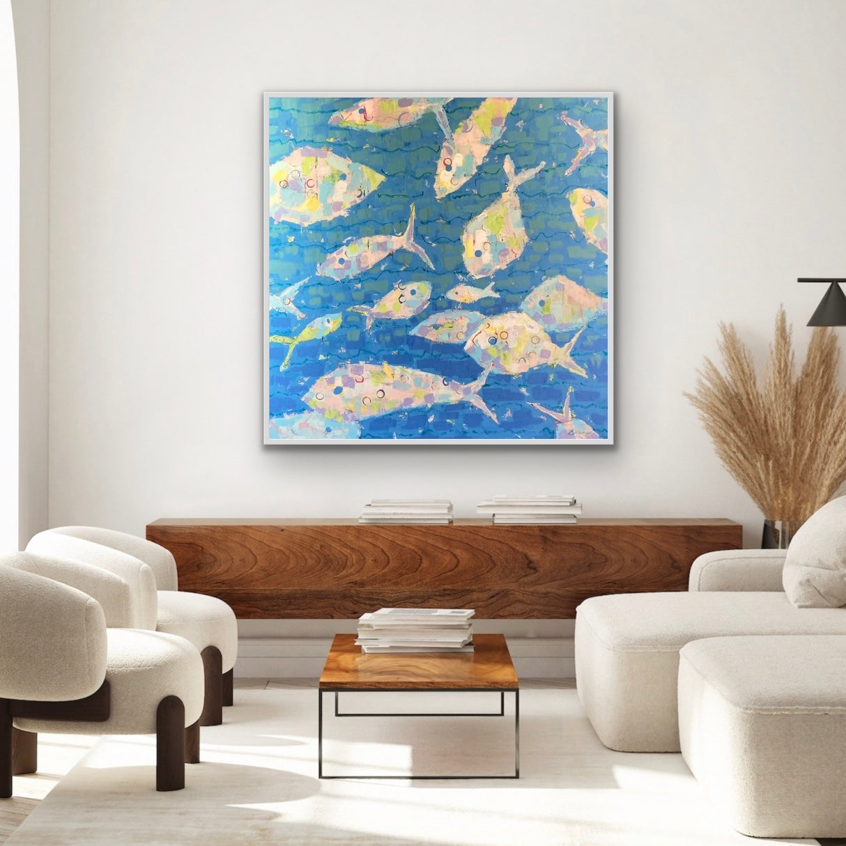 Living room with a colorful abstract sea fish painting on the wall, white sofa, and wooden coffee table.