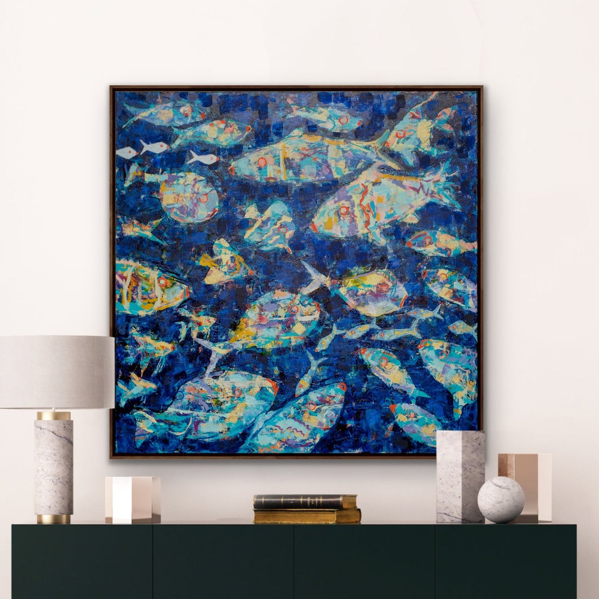 Abstract underwater blue  abstract fish painting above a black cabinet in a room with white walls and floor.