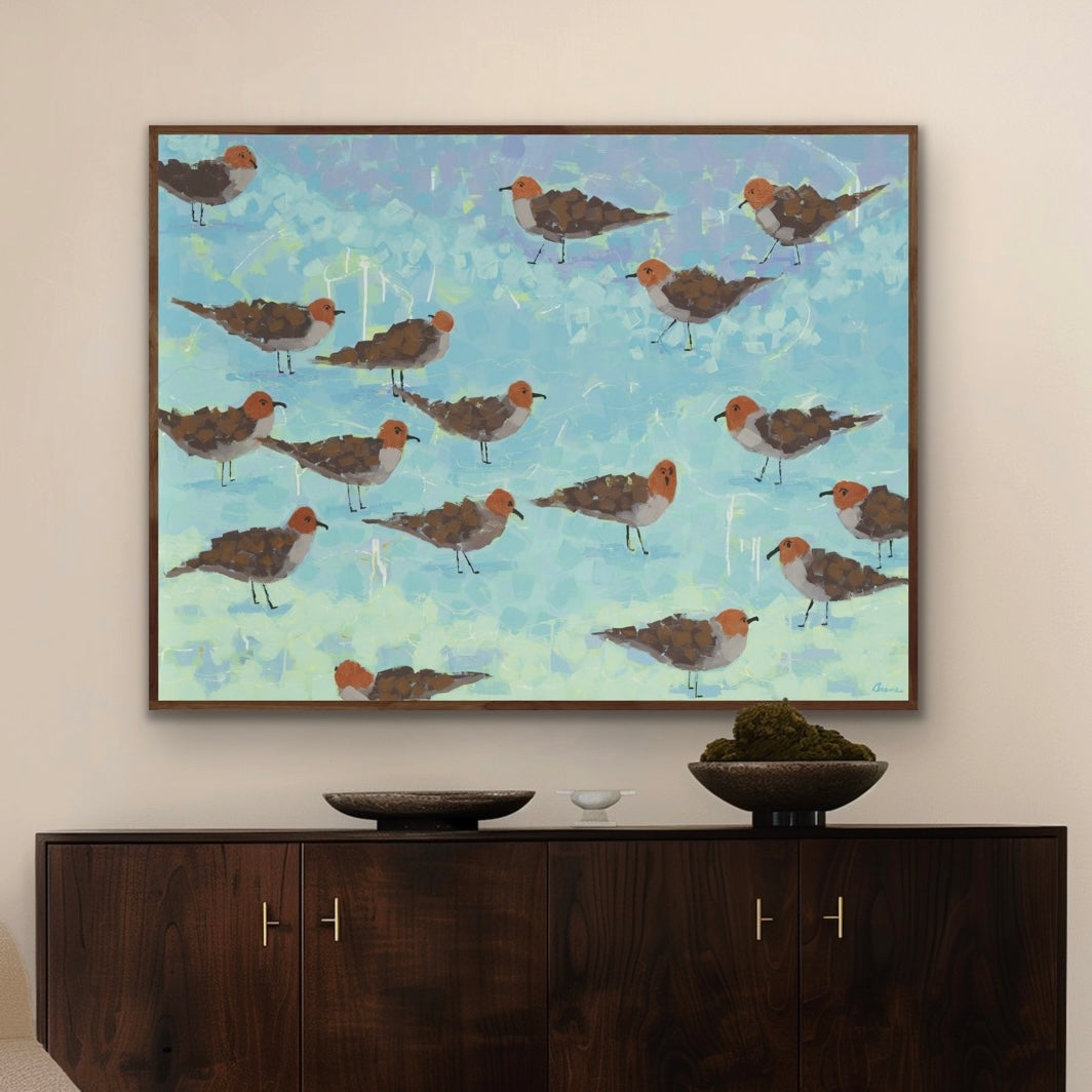 Framed artwork of seagulls on the beach above a wooden cabinet.