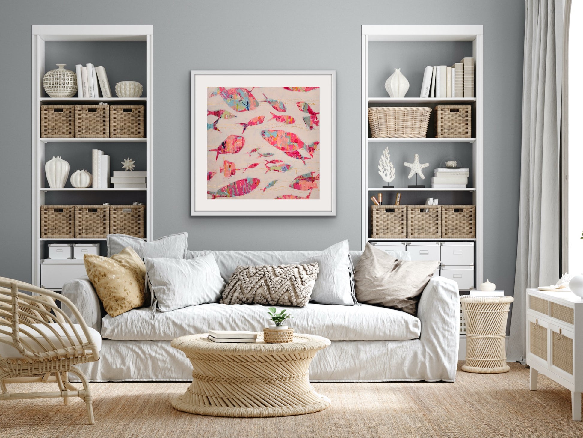 Living room with white sofa, wicker coffee table, and bookshelves with a vibrant coastal fish painting on cotton rag on the wall.