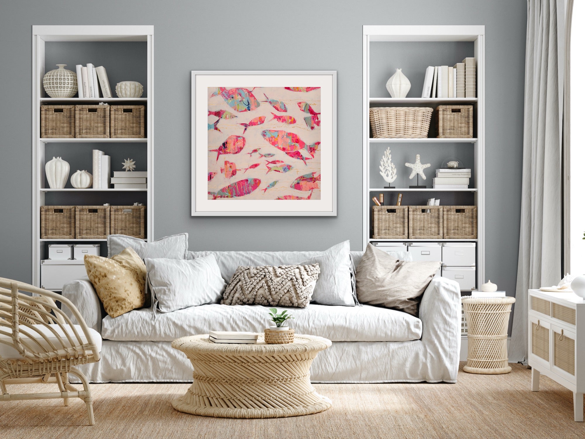 Living room with white sofa, wicker coffee table, and bookshelves with a vibrant coastal fish painting on cotton rag on the wall.