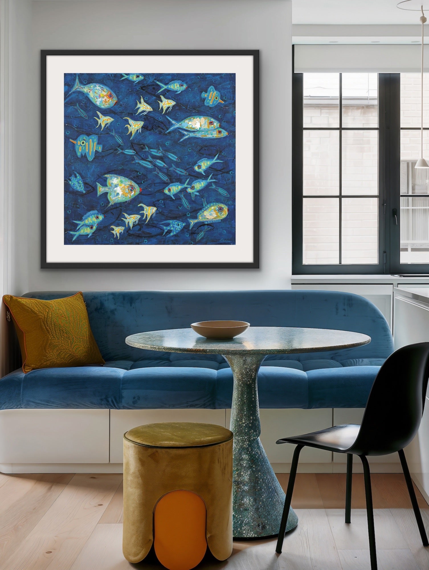 Modern dining room with blue sofa, round table, and colorful coastal abstract fish artwork on the wall.
