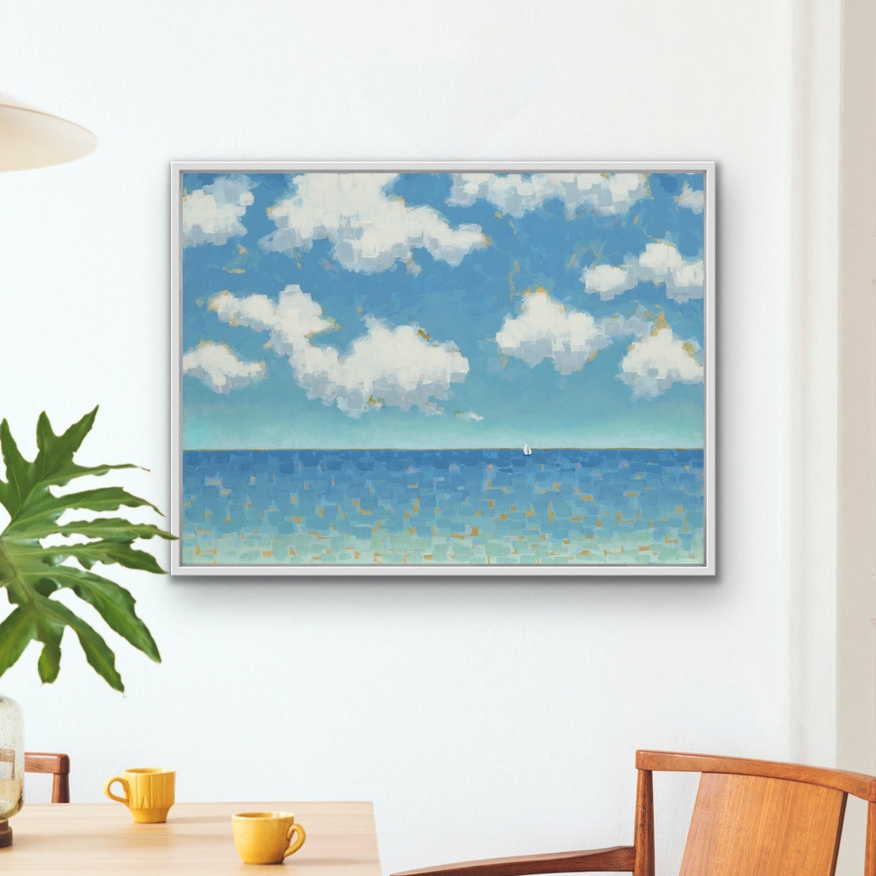 Modern coastal wall art showing clouds drifting above a calm horizon in a room with a table and chairs.