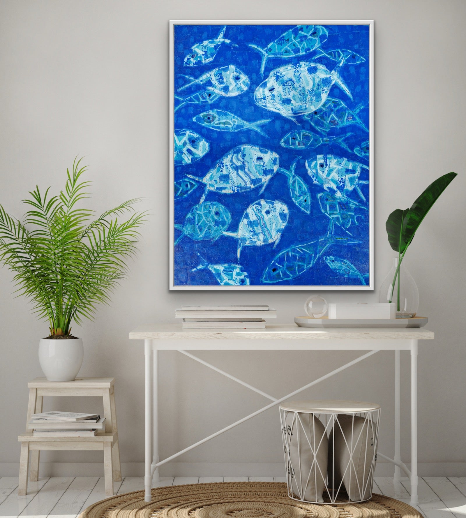Designer abstarct blue fish artwork on a wall above a desk with plants and decor.