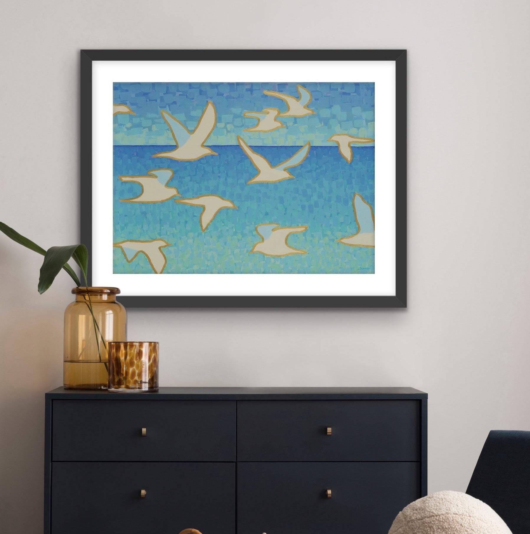 Framed seascape artwork of birds flying over water in a living room setting.