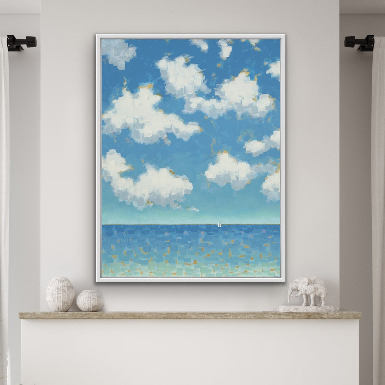 Living room with a fireplace, a vertical coastal canvas print with bright clouds and small sailboat framed and decorative items.