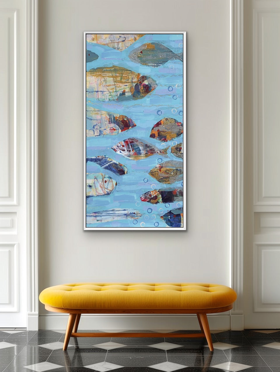 A framed abstract painting of fish swimming in blue water, displayed on a light gray wall above a mustard yellow tufted bench in a classic interior setting.