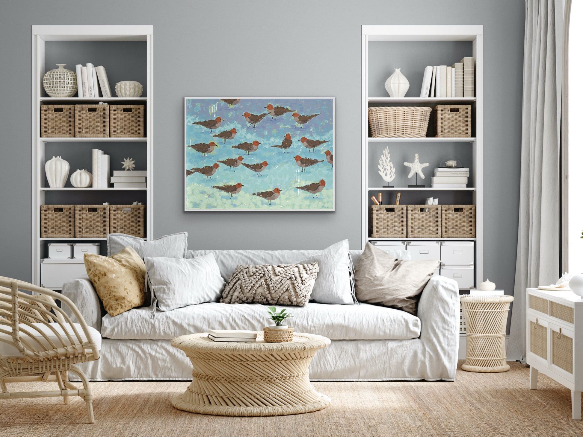Luxury ocean-inspired wall art featuring a flock of seagulls in modern coastal interior with white sofa, wicker coffee table, and bookshelves.