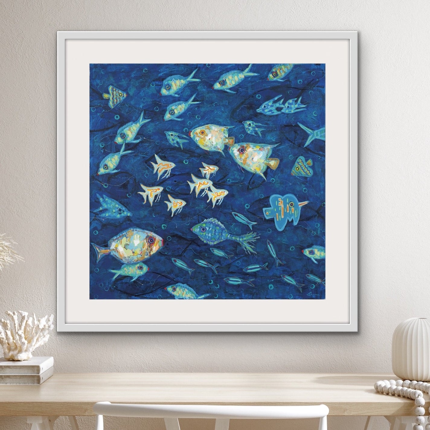 Underwater fish scene framed and matted for coastal interior design on a wall above a table and chairs.