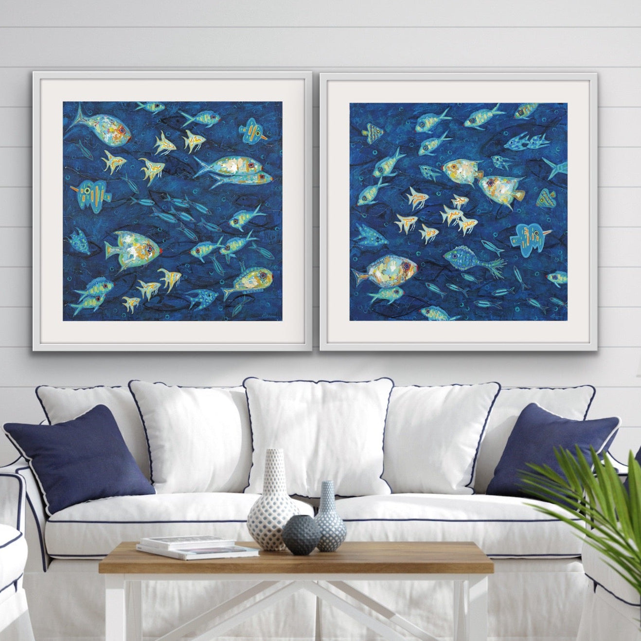 Living room with a white sofa, and wooden coffee table featuring a luxury matted and framed cotton rag diptych featuring vibrant coastal fish in deep ocean blues  for modern coastal and beach home interiors on the wall.