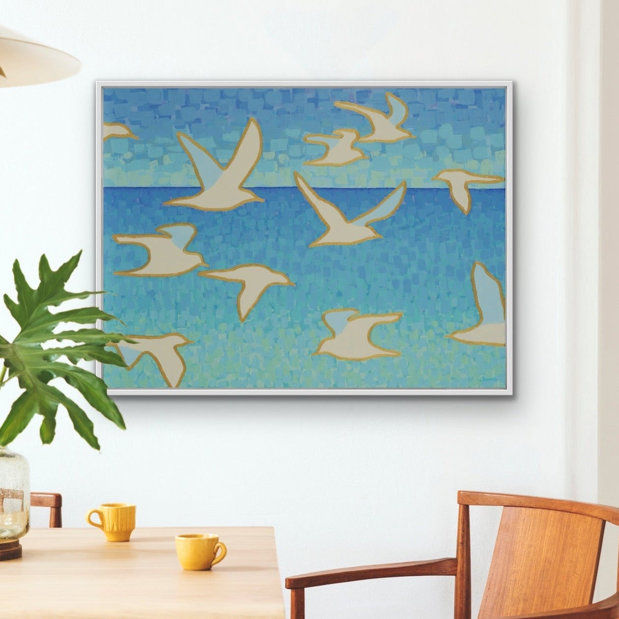 Contemporary coastal artwork in shades of aqua and turquoise, featuring elegant seagulls in flight, luxury fine art print in a dining area with a table, and  chairs.