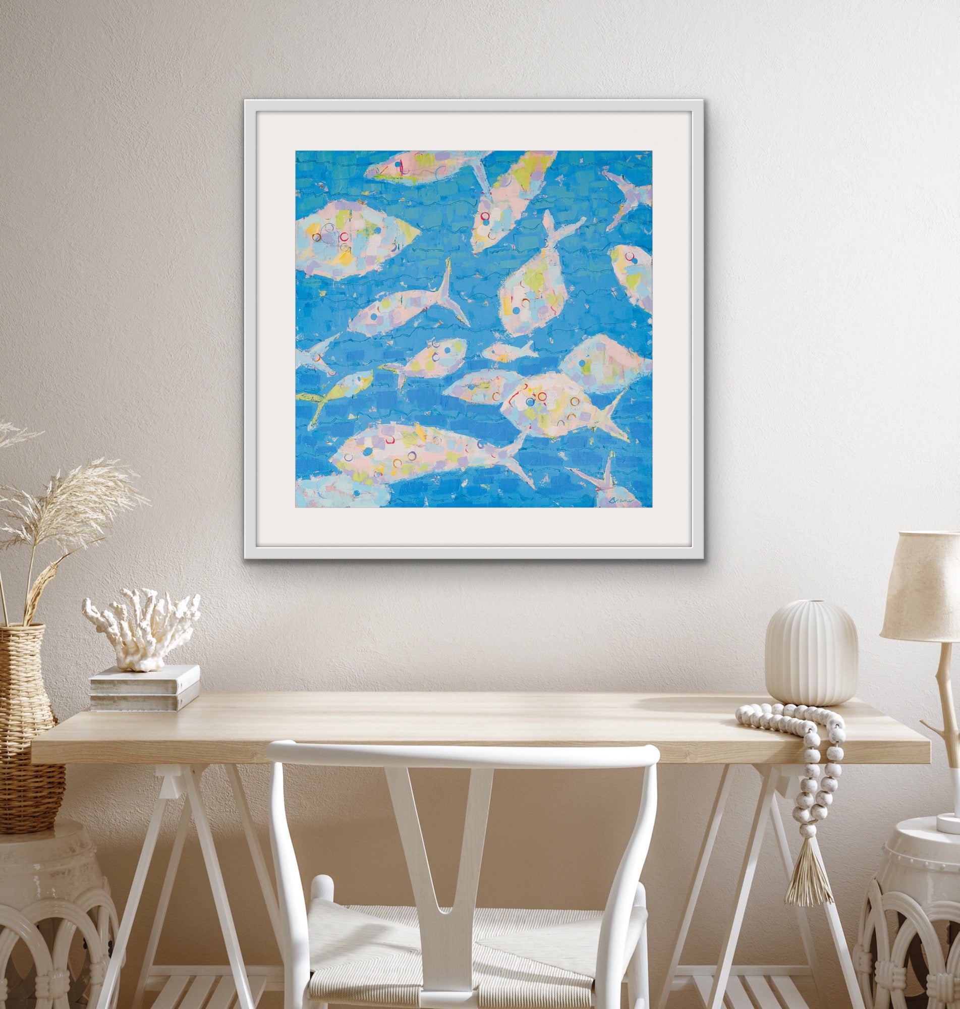 Whimsical underwater scene in pastel tones framed artwork on a wall above a wooden table.