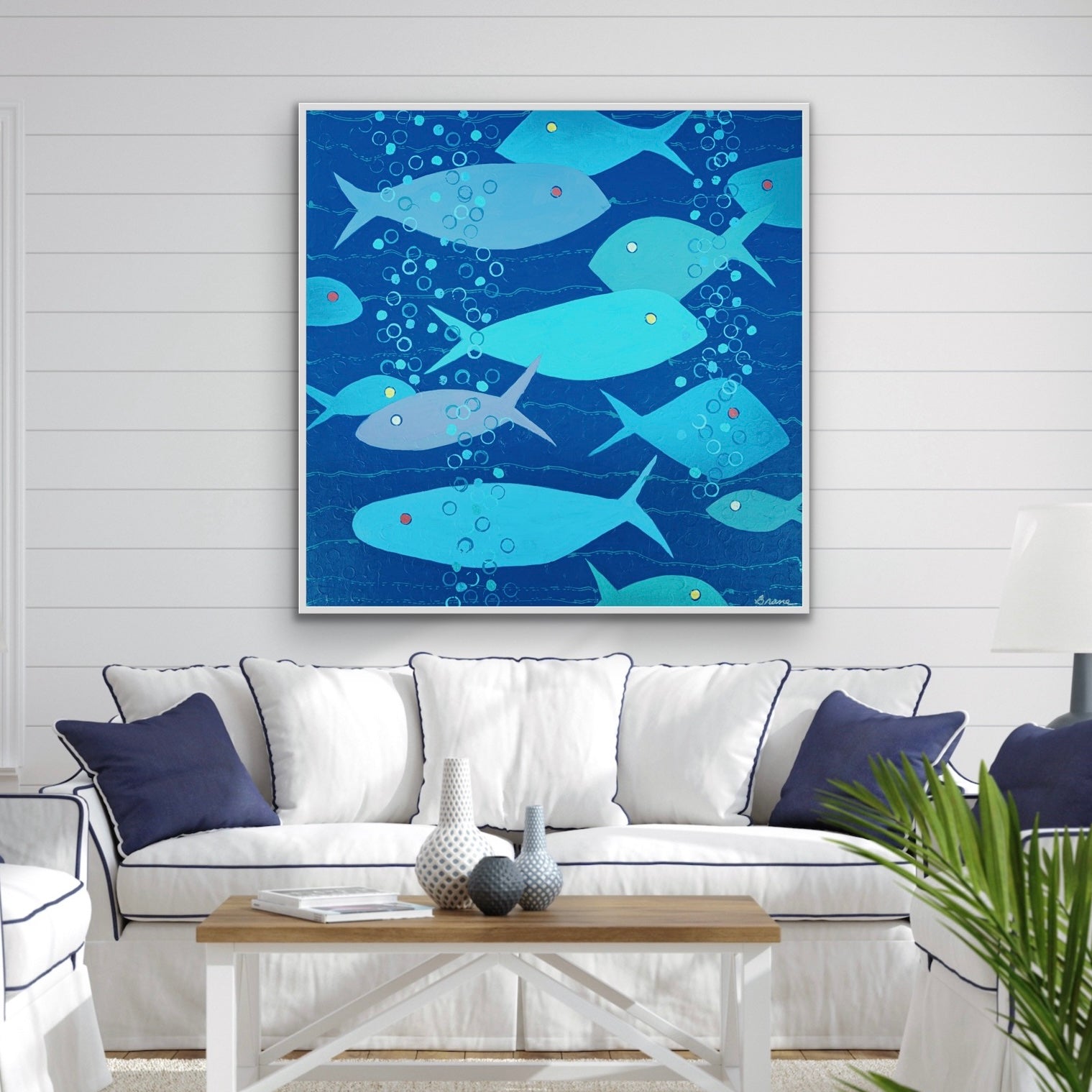 Living room with a contemporary blue fish artwork on the wall above a white sofa.