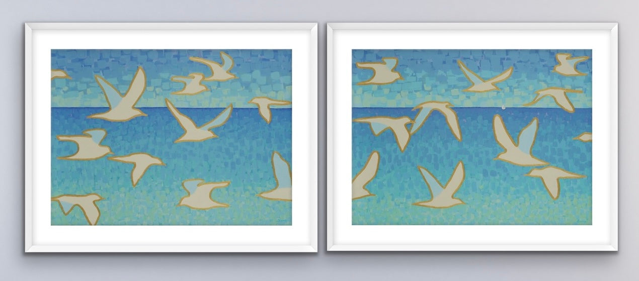 Two white framed  seascape artworks of birds flying over water with a blue sky.