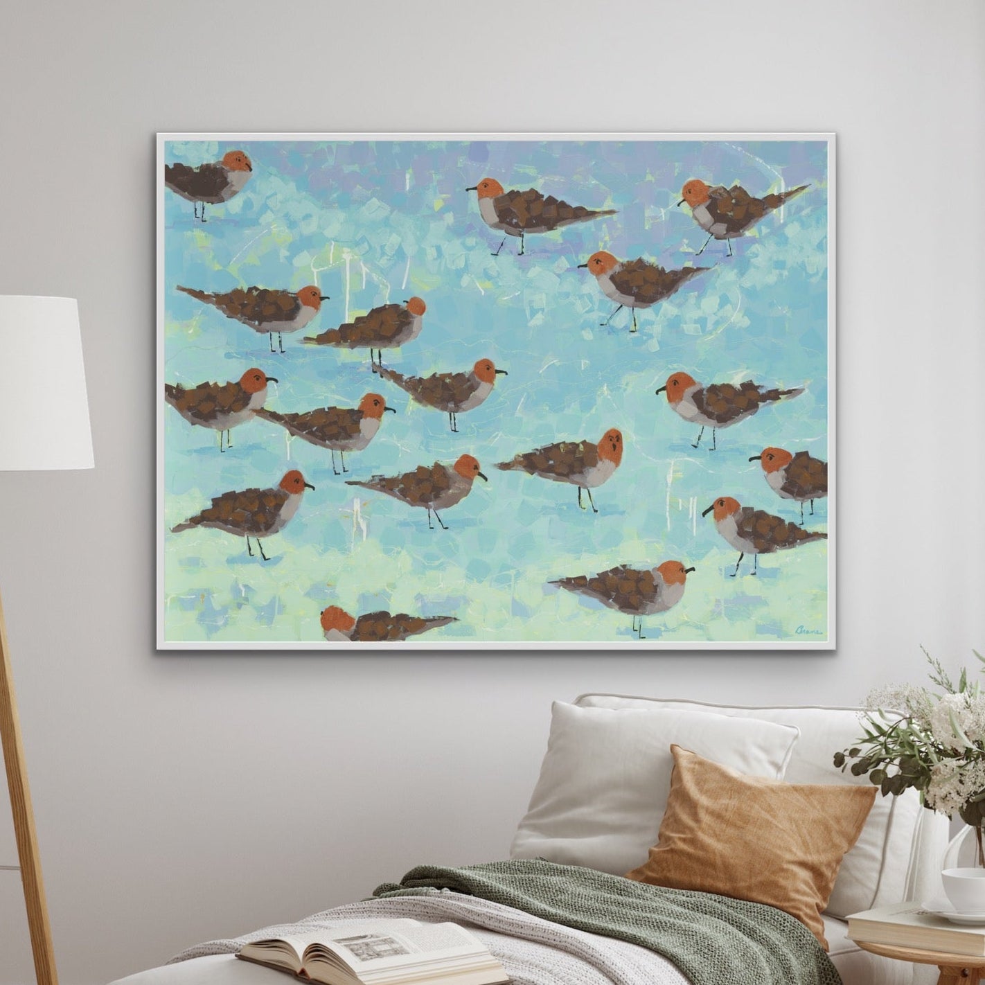 Shorebird giclée canvas print with turquoise and coral tones by Martha Brane in a living room with a lamp and a sofa.