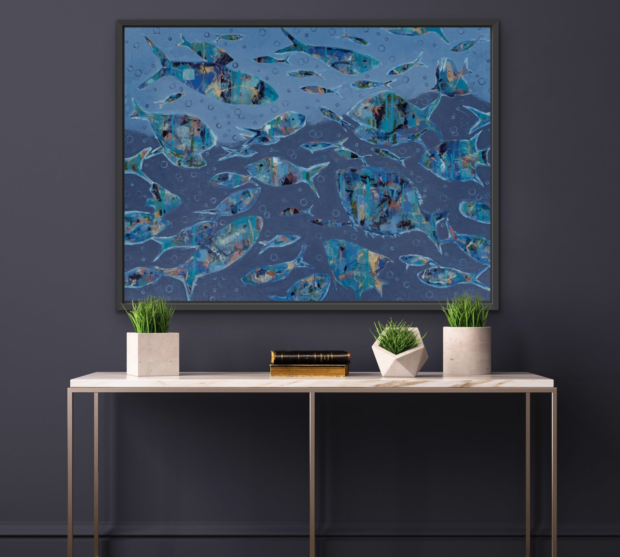 A framed abstract art print depicting a school of fish in shades of blue and teal, displayed on a dark gray wall above a modern console table with plants.