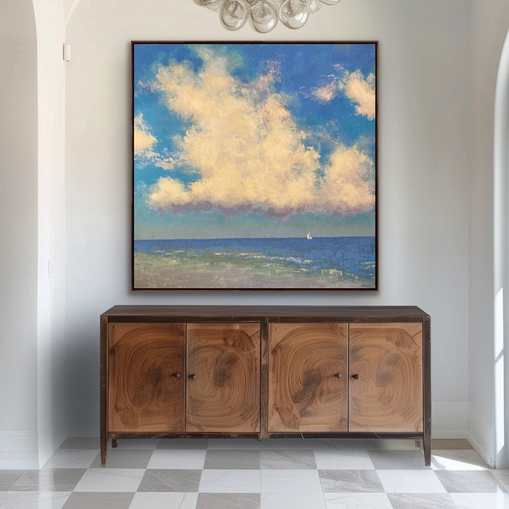 Foyer with wooden cabinet, chandelier, and large painting of clouds and ocean.