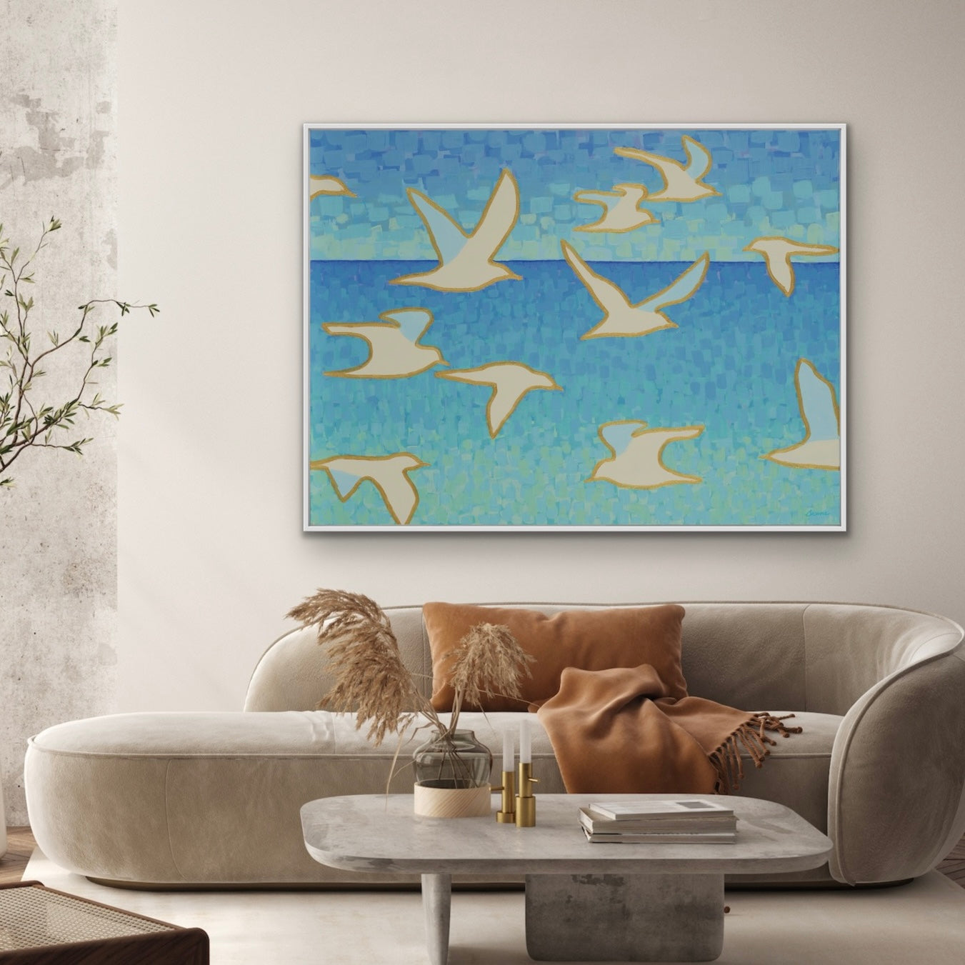 Living room with a sofa, coffee table, and abstract seagulls flying over the sea on the wall.