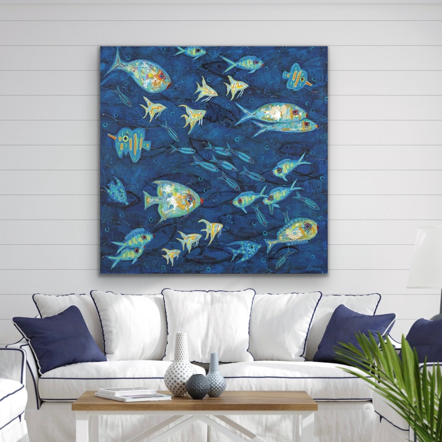 Framed artwork of abstract coastal ocean fish on a blue background in a living room setting.