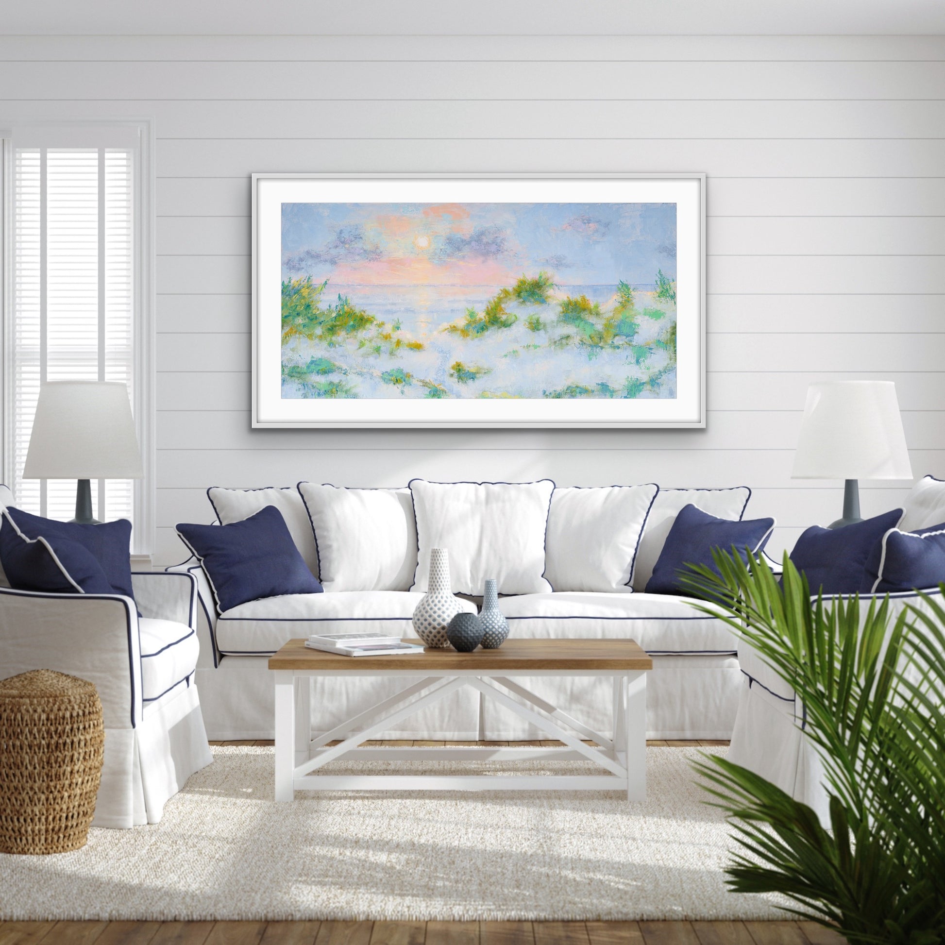 Living room with a white sofa, wooden coffee table, and  a wide-format cotton rag seascape framed with white mat artwork on the wall.