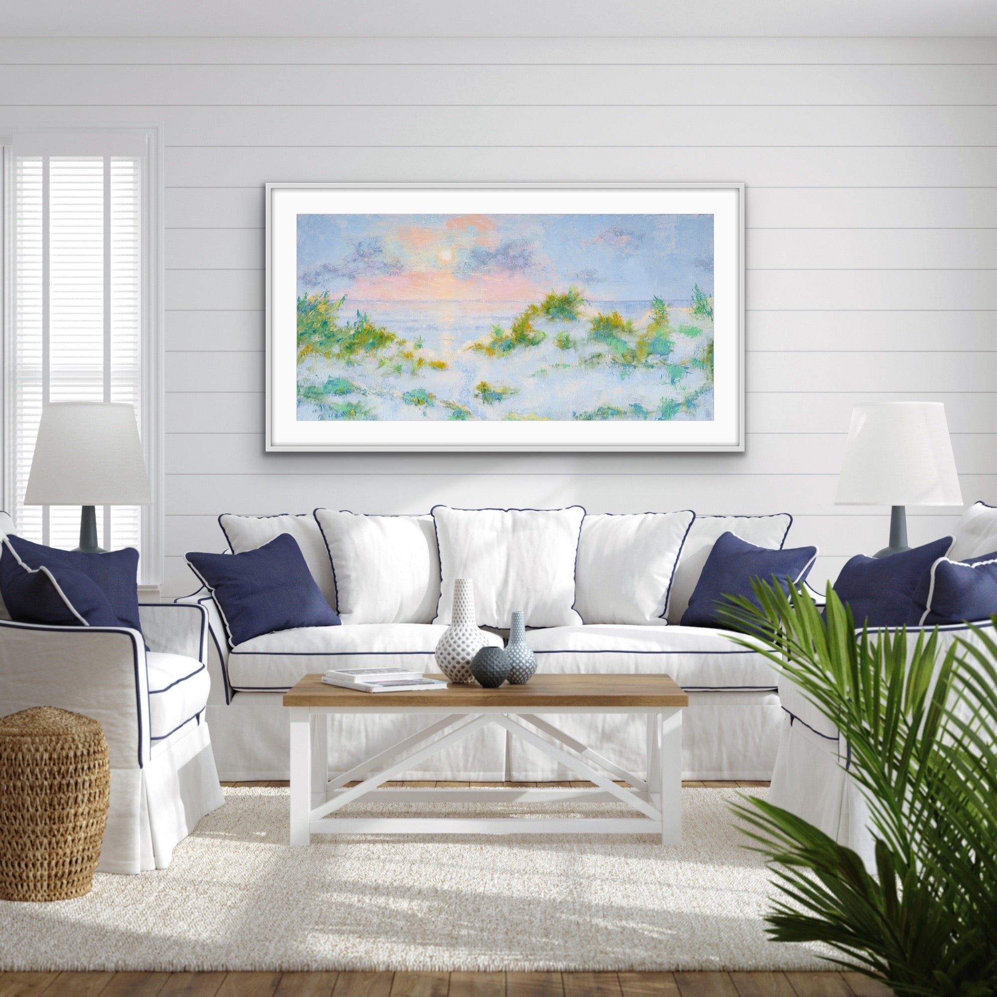 Living room with a white sofa, wooden coffee table, and  a wide-format cotton rag seascape framed with white mat artwork on the wall.