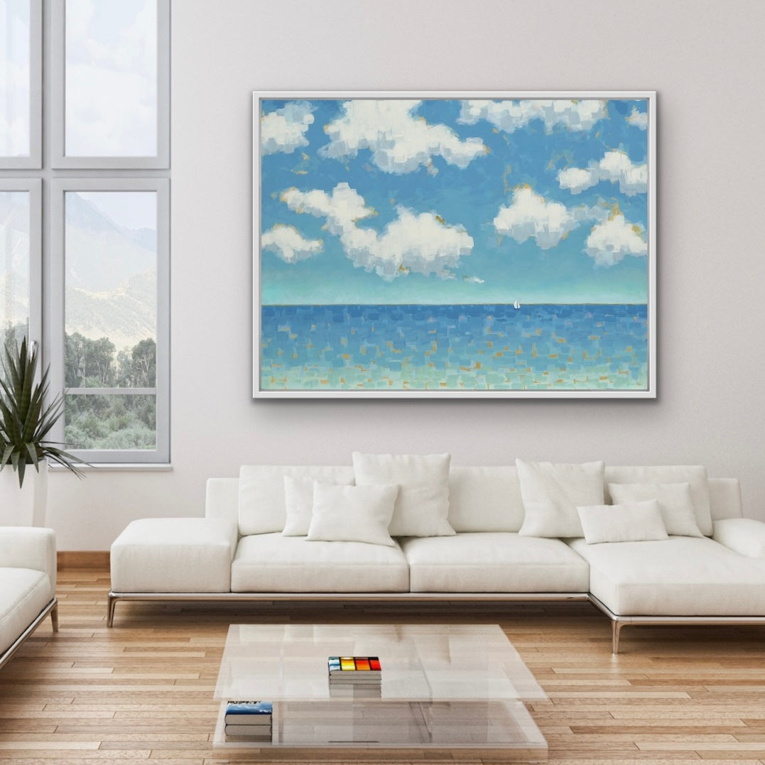 Modern living room with a large white sofa, glass coffee table, and a framed oceanscape with sailboat with clouds painting on the wall.