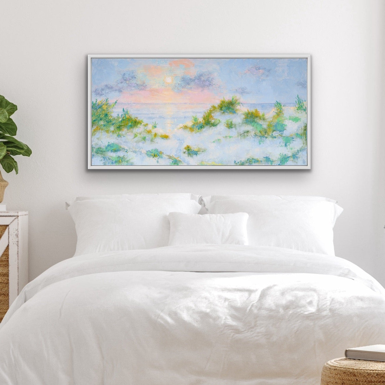 Neatly made bed in a bright bedroom with plants and a wide-format beach sunrise giclée print on the wall.