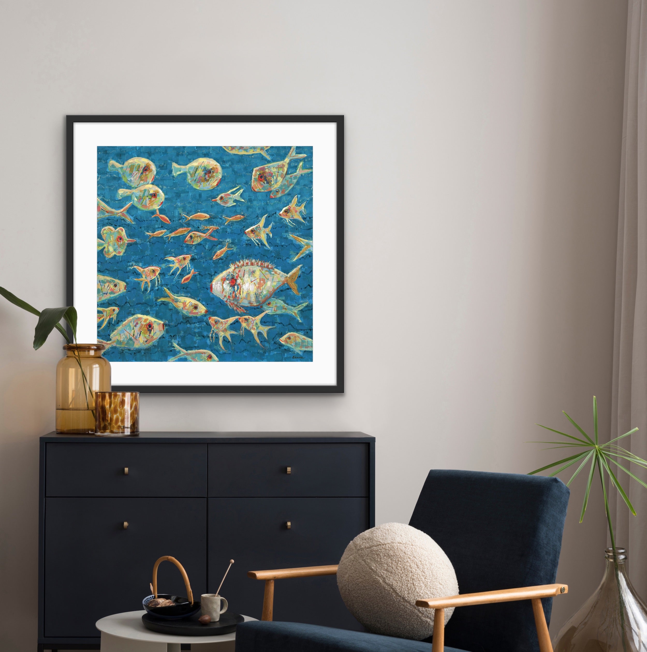 Framed large statement artwork of colorful fish on a blue background in a living room setting.