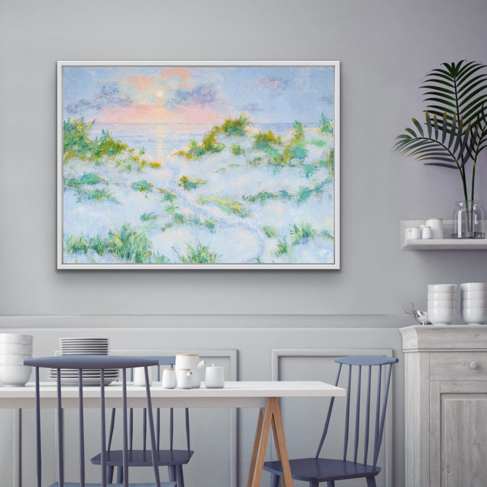 Dining room with a table and chairs, a horizontal coastal sunrise canvas print with dunesa large framed painting on the wall, and a shelf with decorative items.