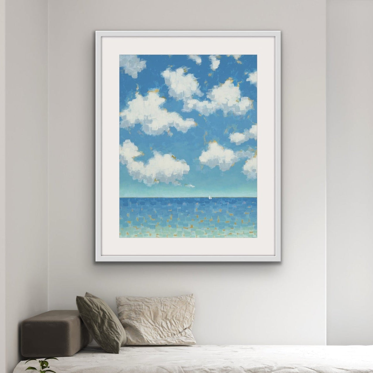 Vertical coastal artwork with clouds and sailboat and a blue sky with clouds in a minimalistic room.