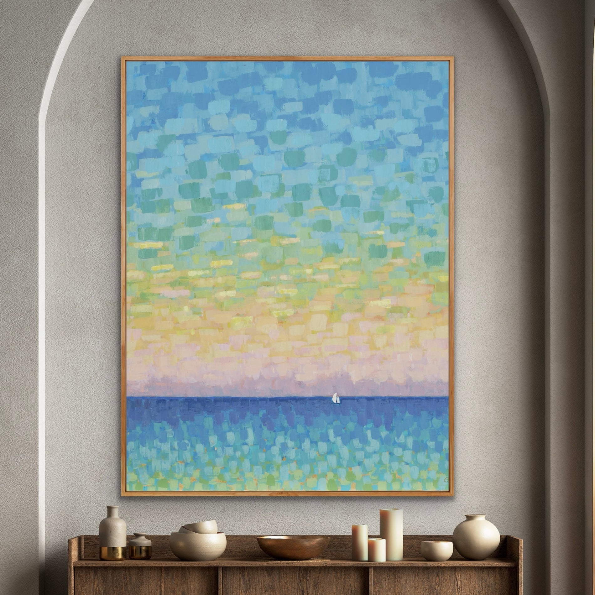 Abstract coastal seascape art painting on a wall above a wooden console table with decorative items.