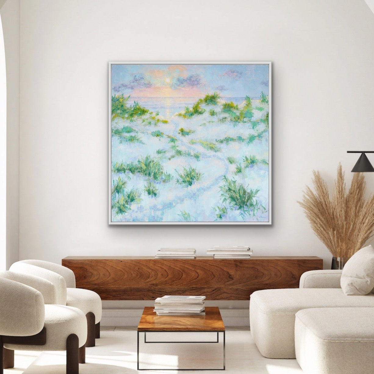 Modern living room with white walls, a wooden coffee table, and a large sunrise seascape with dunes abstract painting.
