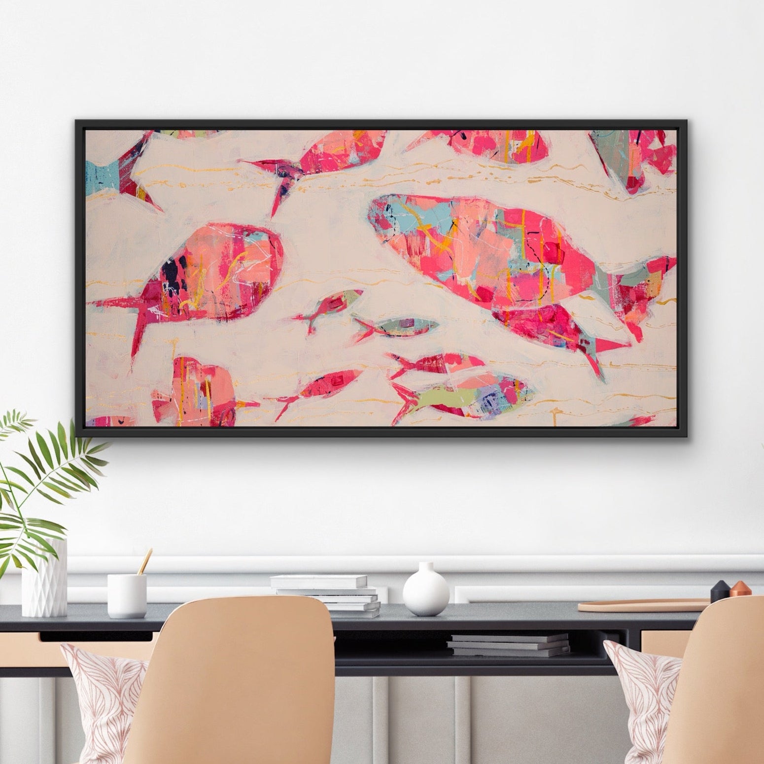 Panoramic coastal canvas featuring abstract pink and coral fish by Martha Brane on a wall above a desk with chairs.