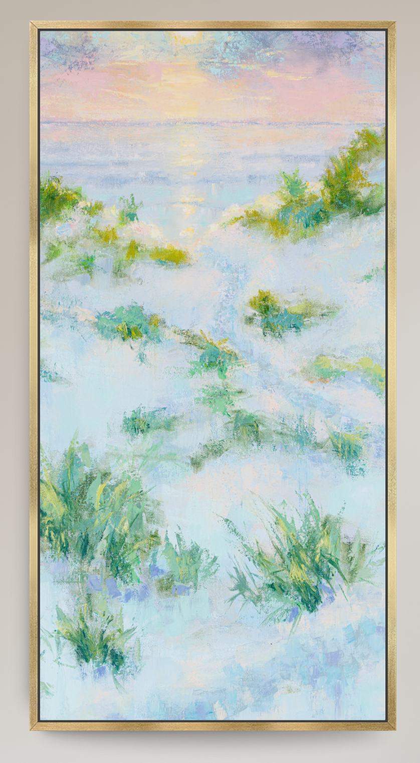 A framed vertical landscape painting depicting a misty coastal scene with green grasses in the foreground, a soft blue and white sea, and a pastel sky with pink and yellow tones, enclosed in a thin gold frame.