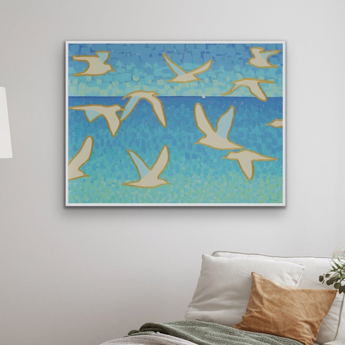 Contemporary coastal artwork in shades of aqua and turquoise, featuring elegant seagulls in flight, a luxury fine art print in a living room with a lamp, and a sofa.