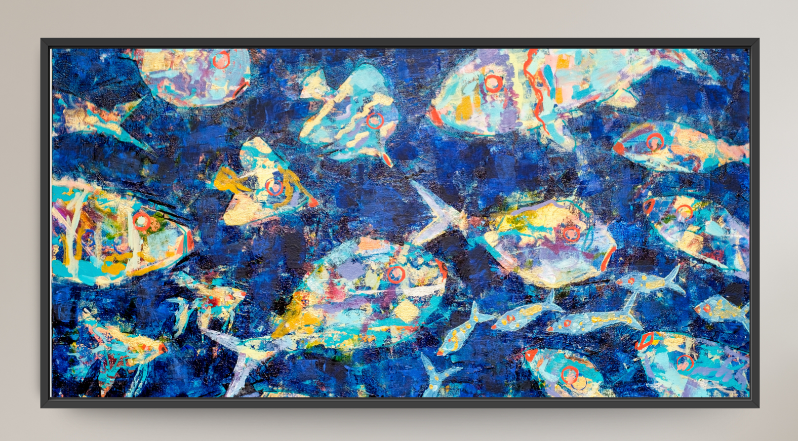 A framed abstract art print depicting stylized blue and light blue fish swimming underwater with bubbles, set against a neutral beige wall.