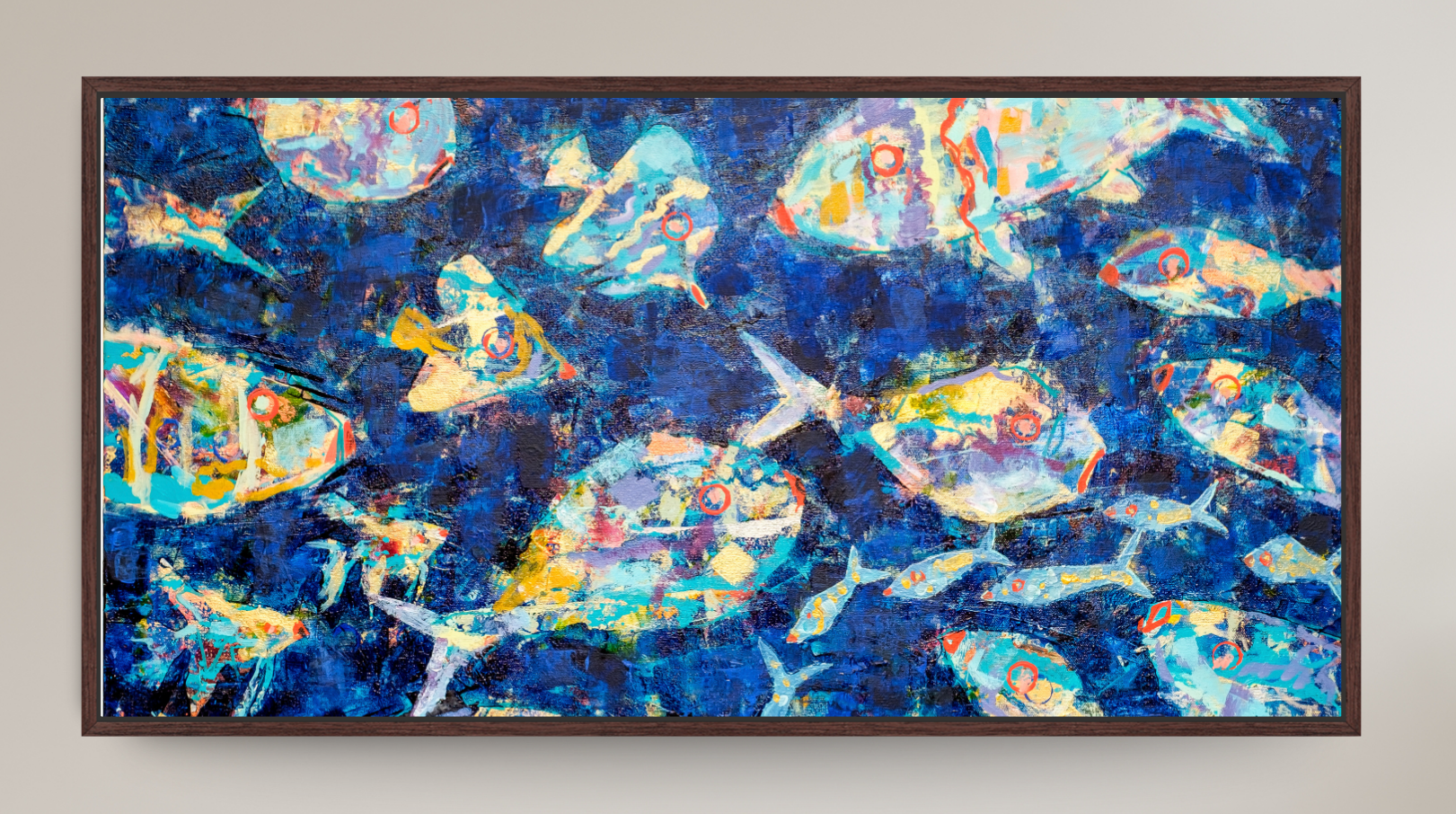 A framed abstract art print depicting stylized blue fish swimming underwater with bubbles, set against a light beige wall.