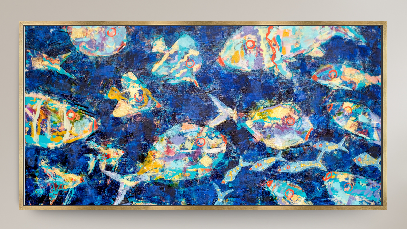 A framed square art print depicting stylized light blue fish swimming in a deep blue underwater scene with white bubbles, set against a light beige wall.