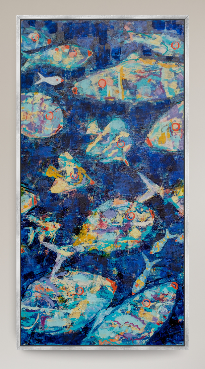 A framed abstract painting featuring blue fish motifs hangs on a light beige wall in a modern living room setting with a gray armchair, small potted plant, and decorative cat statue.