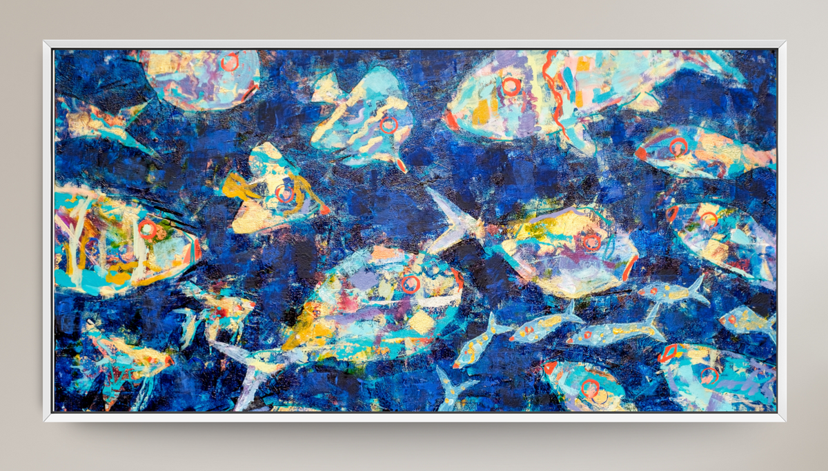 A framed abstract art print depicting stylized blue fish and bubbles on a deep blue background, mounted on a light beige wall.