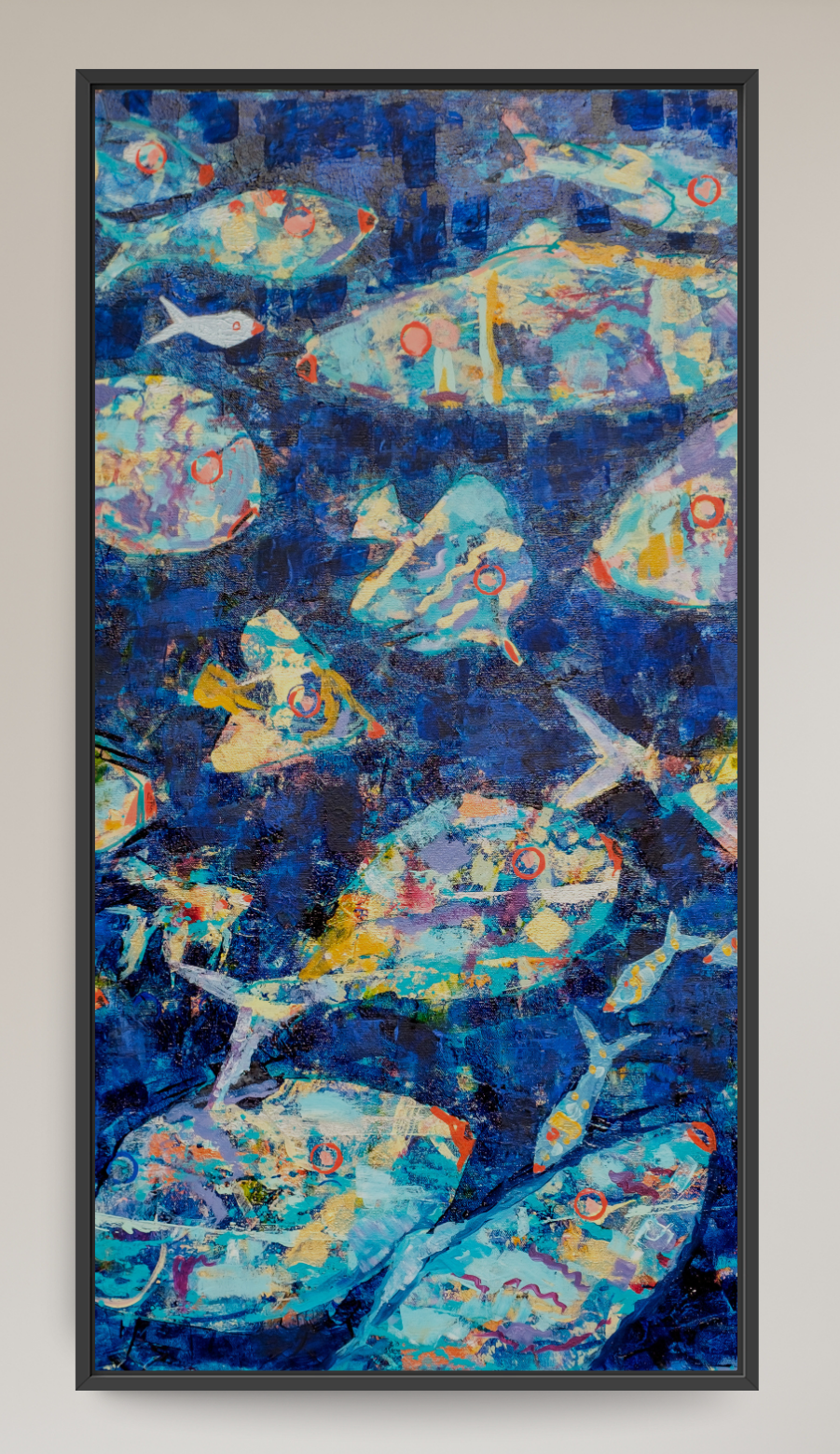 A framed abstract canvas print featuring a school of fish in deep blue and teal tones, displayed on a light beige wall in a modern living room setting next to a gray armchair.