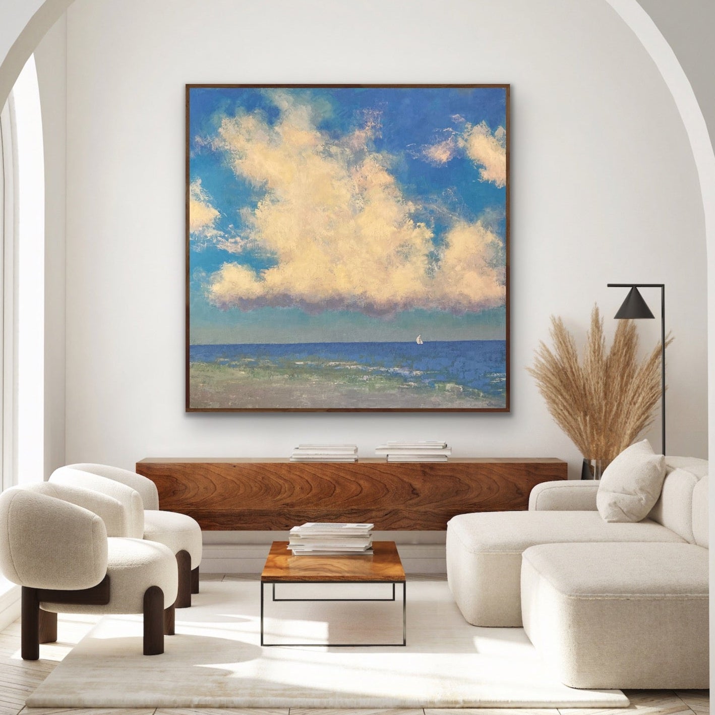 Modern living room with a large abstract seascape painting of clouds, white furniture, and a wooden coffee table.